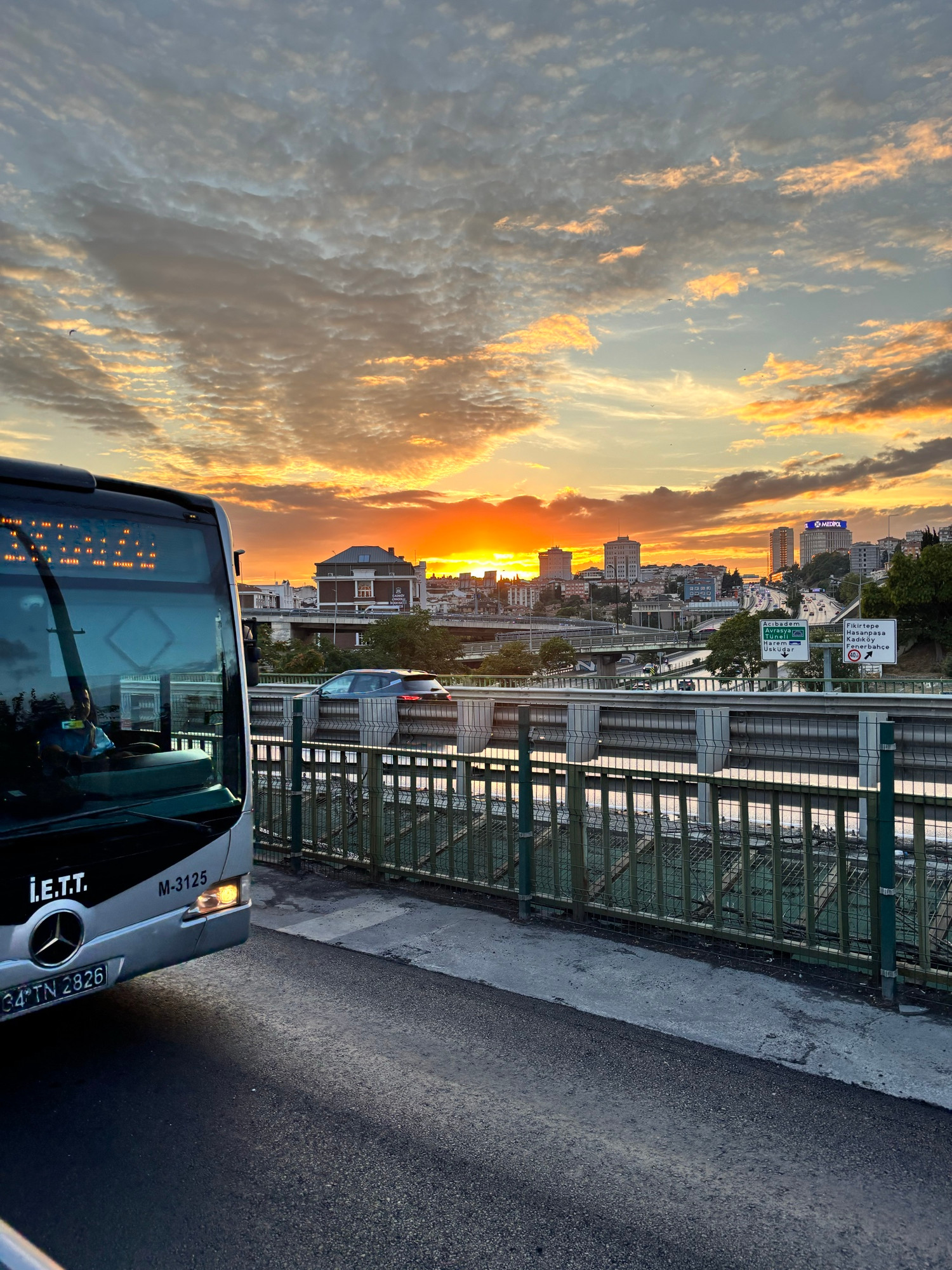 An İETT bus beneath a gold and orange evening sky in Istanbul.