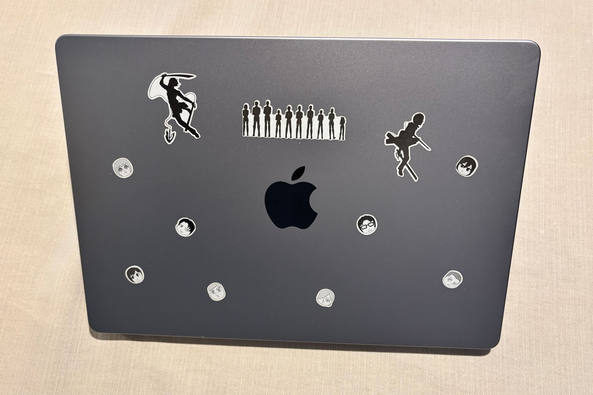 My closed MacBook, with black-and-white Attack on Titan stickers around the Apple logo.