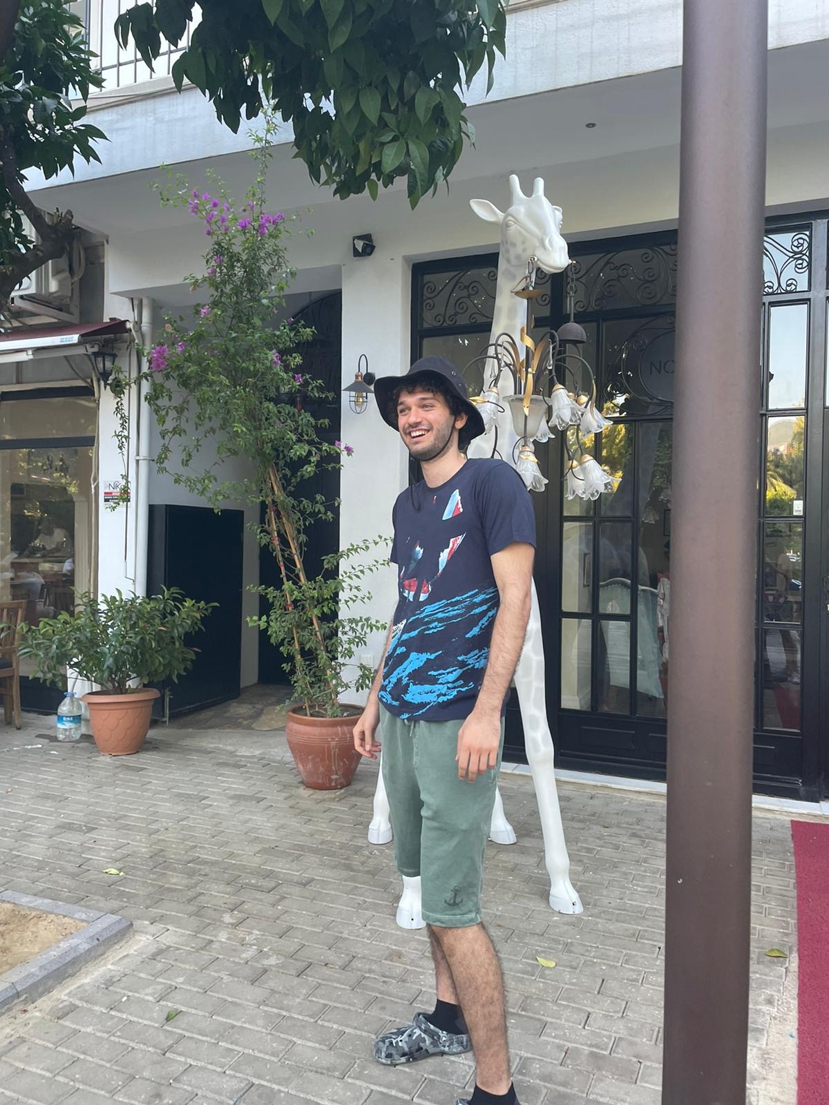 Selçuk’ta beyaz zürafa figürlü bir lambanın önünde gülen Doğukan.